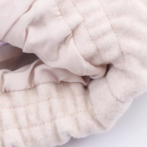 Detailed macro view of quilted cream fabric with soft plush texture and smooth silk-like lining