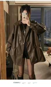 Detail of double-breasted brown PU leather jacket featuring drawstring waist and dropped shoulders