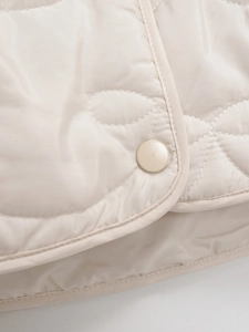Macro shot of beige quilted jacket detail with flower pattern stitching and matte snap button