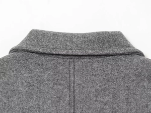 Detailed view of the lapel and thick grey wool-blend fabric texture of the winter coat