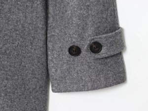 Detail of grey wool coat cuff featuring adjustable strap and faux tortoise buttons