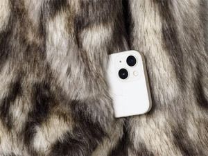 Nahaufnahme der gestreiften Kunstpelzjacke mit einem weißen Smartphone in der Tasche