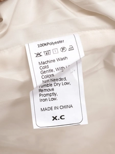 Close-up of the wash care label showing 100 percent polyester content on quilted jacket
