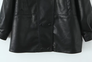 Detail of double-breasted black PU leather jacket showing pockets and hemline texture