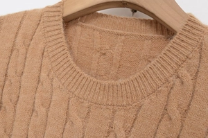 Close-up of camel cable knit sweater showing ribbed crew neck and textured wool fabric