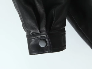 Detailed macro view of black PU leather jacket cuff with snap button and stitching