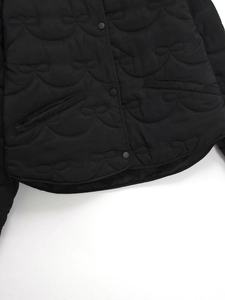 Detail of black quilted jacket with scalloped stitching and delicate bow embroidery