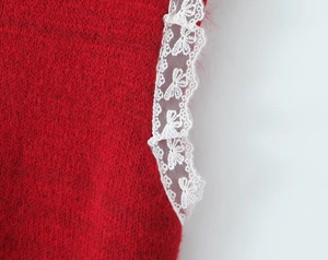 Close-up of red knitted vest featuring delicate white floral embroidery lace details