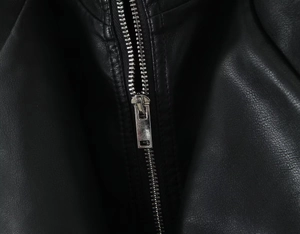 Detailed macro view of high-quality silver metal zipper on a black faux leather jacket