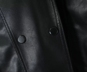 Detail of black PU leather texture with matte snap buttons and vertical stitching