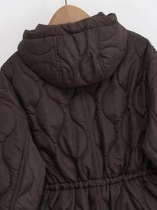 Detail of brown quilted jacket featuring a stylish wave pattern and adjustable waist drawstring