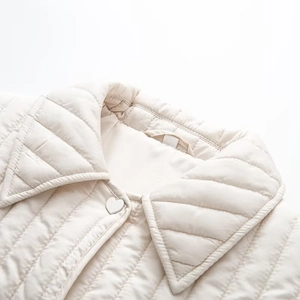 Detail of vertical quilting texture and decorative white heart-shaped buttons on cream jacket