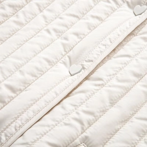 Detailed view of cream quilted jacket with decorative white heart-shaped button fasteners