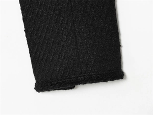Detailed macro view of the black tweed jacket cuff showing premium weave and stitching
