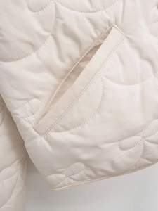 Detailed macro view of wavy quilted fabric and flat pockets on the cream white jacket