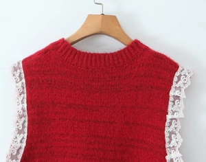 Detail of red knit vest with round neck and white lace trim on sleeveless armholes