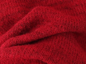 Macro detail of red knit fabric with soft wool texture and intricate stitching