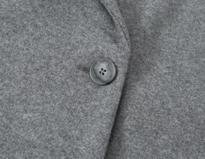 Macro detail of high-quality grey wool coat fabric with a marble textured button