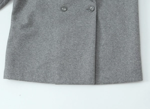 Close-up of gray wool coat hem with detailed fabric texture and dark buttons