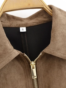 Detailed macro view of the brown suede jacket's golden zipper and collar with size label S