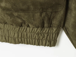 Détail de l'ourlet élastique et des coutures sur une veste en daim vert olive