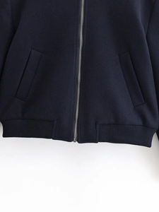 Detail view of navy blue jacket with silver zipper, side pockets and ribbed hem texture