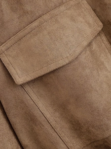 Detail of brown suede jacket showing flap pocket design and precise stitching finish