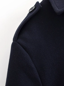 Close-up detail of dark navy wool jacket shoulder featuring buttoned epaulette design