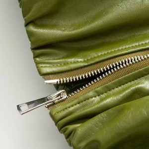 Detail of green PU leather texture with stylish gathered design and silver metal zipper
