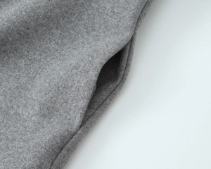 Detailed macro view of the grey wool blend fabric and side seam pocket of the winter coat
