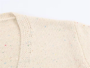 Macro detail of beige knit sweater showing colorful specks and neckline stitching