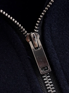 Detailed macro view of high-quality silver metal zipper on navy blue fleece jacket