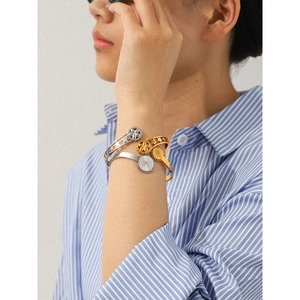 Detail of stacked two-tone geometric bracelets with hollow flower and sun charm