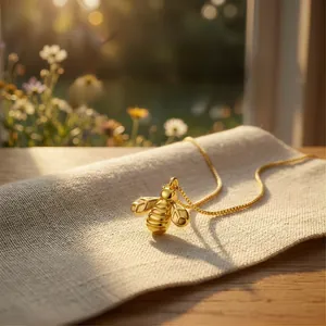 Close-up of a detailed 18K gold-plated bee pendant necklace on a linen surface