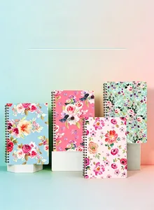 Detail view of four floral hardback spiral notebooks with black metal coils on white blocks
