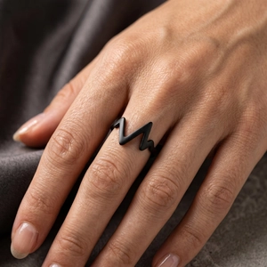 Macro shot of matte black stainless steel lightning zig zag ring on dark textured fabric
