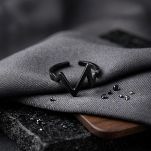 Macro detail of matte black lightning pulse ring on textured grey fabric background