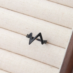 Macro view of black heartbeat pulse wave ring displayed in a beige jewelry box slot