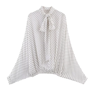 Dettaglio della camicetta bianca a pois con scollo a fiocco e polsini elastici sul retro