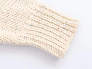 Close-up of cream knit sweater cuff featuring colorful rainbow flecks and ribbed texture