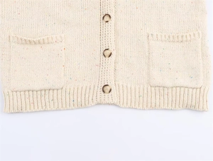 Detail of speckled off-white knit cardigan showing tortoiseshell buttons and ribbing