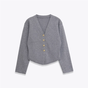 Detail of grey V-neck knit cardigan with embossed gold buttons on white background