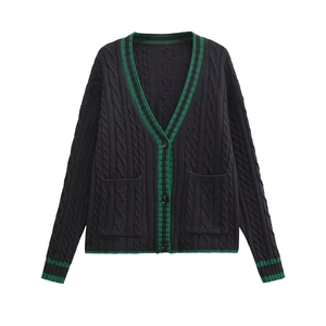 Detail of cable knit cardigan with contrast green stripes and textured black fabric