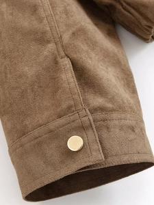Detail of brown faux suede jacket sleeve with golden metal button and neat stitching