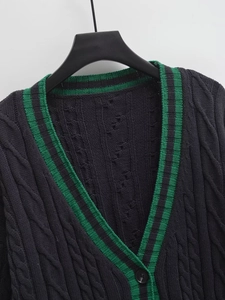 Detailed cable knit pattern on V-neck cardigan with contrasting green stripe trim