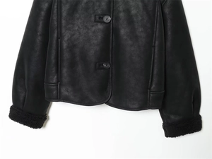 Détail d'une veste noire en similicuir avec poignets en peau lainée et boutons