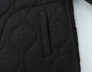Detail of black onion quilted jacket fabric with side pocket and neat stitching