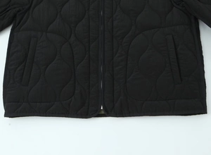 Close-up of black quilted jacket featuring wave stitching pattern and zipper detail