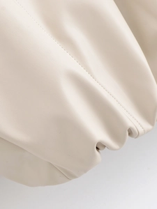 Macro shot of fine stitching on beige PU leather jacket fabric with smooth texture