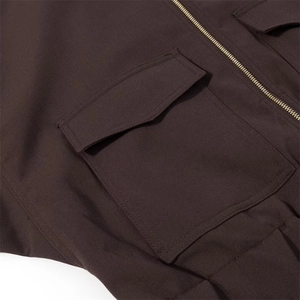 Close-up of a brown casual jacket featuring a large flap pocket and a gold zipper detail